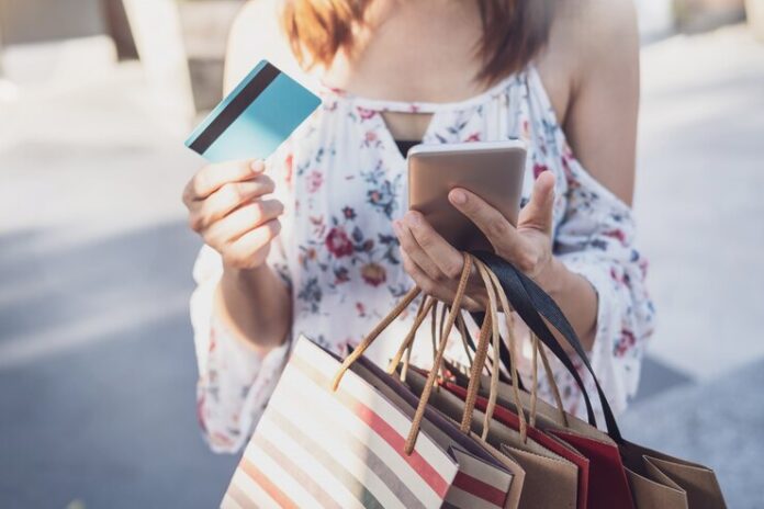 young-woman-using-smartphone-with-shopping-bags-credit-card-shopping-mall-black-friday_44943-533