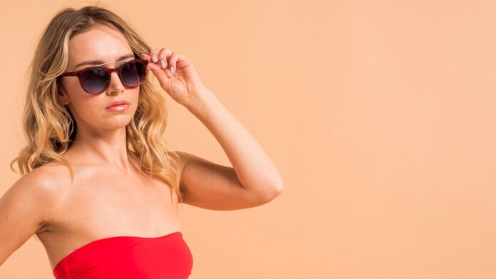young-blond-woman-red-top-sunglasses-orange-background_23-2148135776